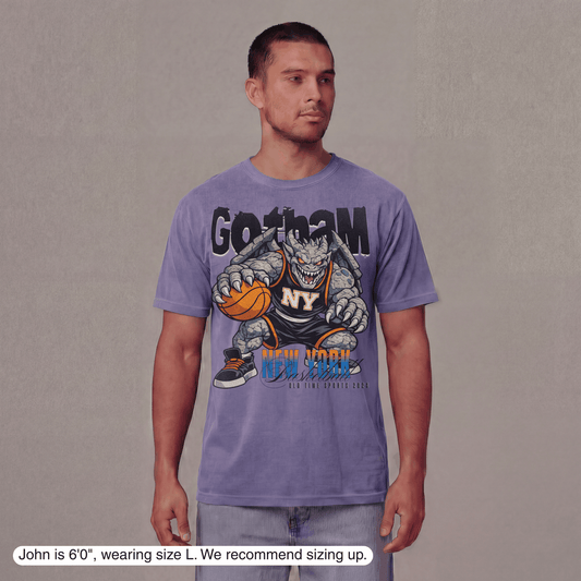 Man wearing a purple t-shirt with a graphic design on a plain background